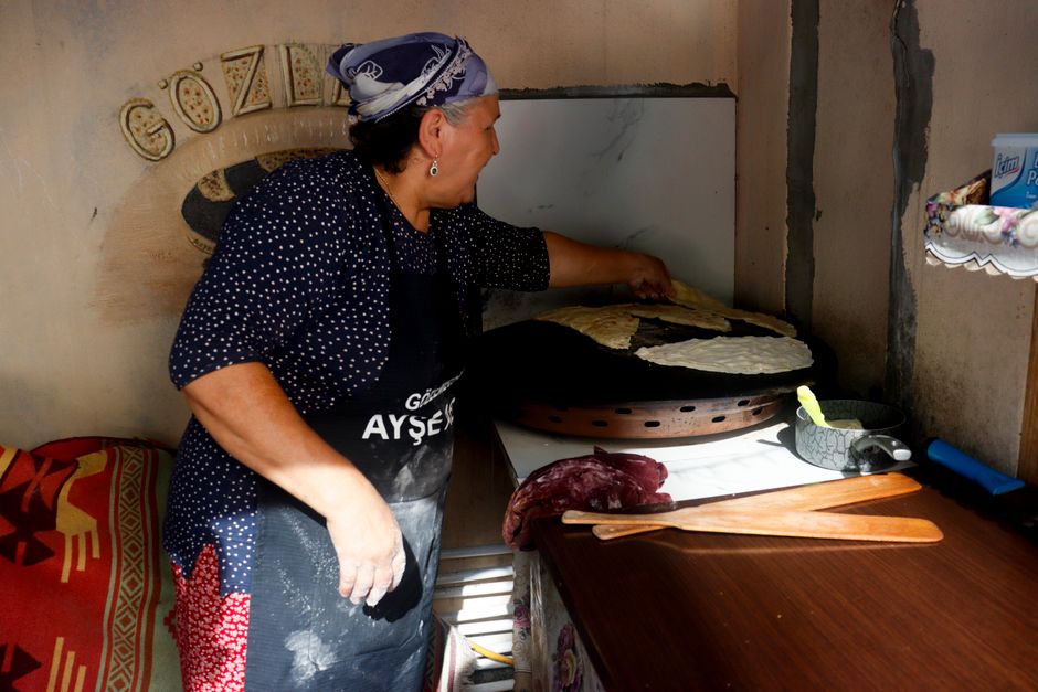 A woman prepares traditional Turkish gözleme indoors at a local kitchen in Istanbul, Türkiye.