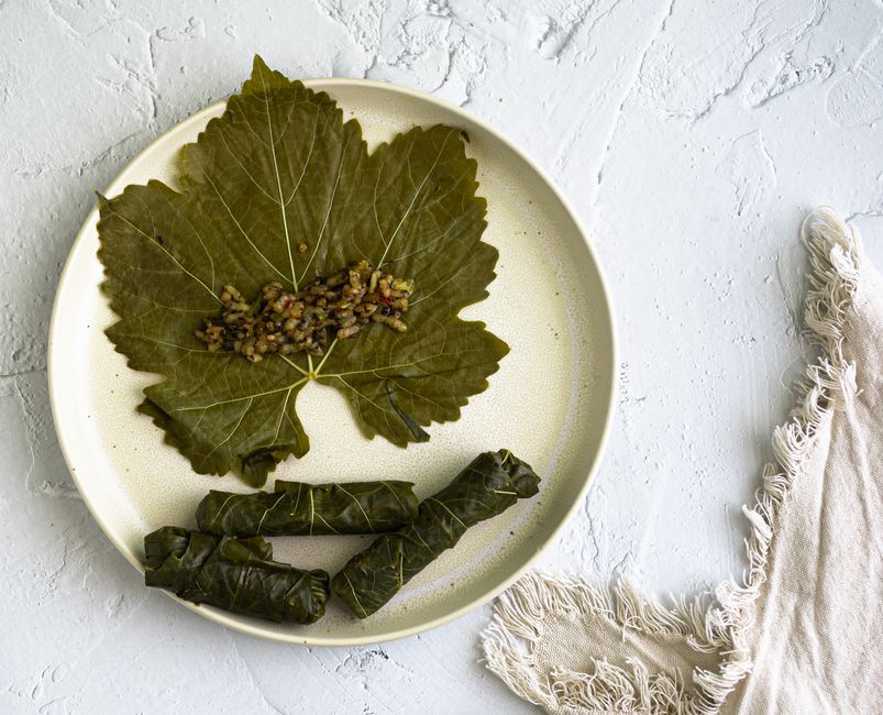Close-up of homemade dolma yalanji with grape leaves on a textured plate.